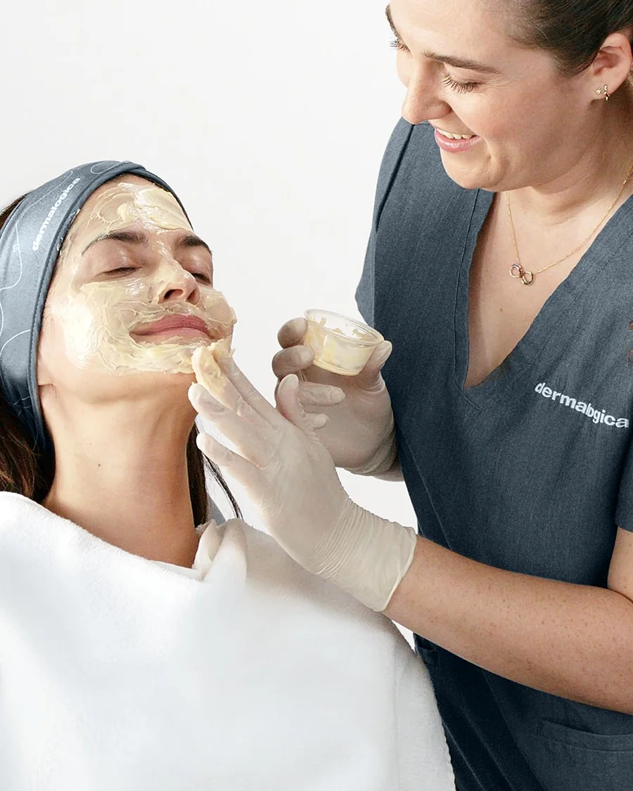 Kosmetikerin trägt die MelanoPro Peeling Maske im Studio auf
